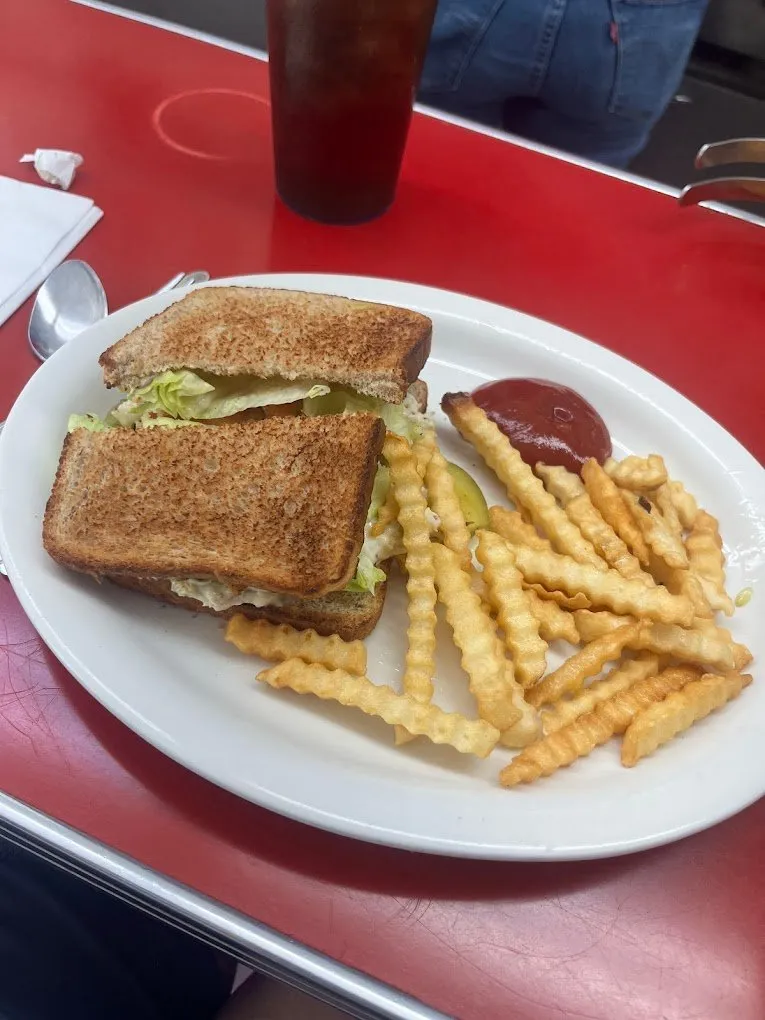 A toasted BLT with crinkle-cut fries and ketchup on the red counter